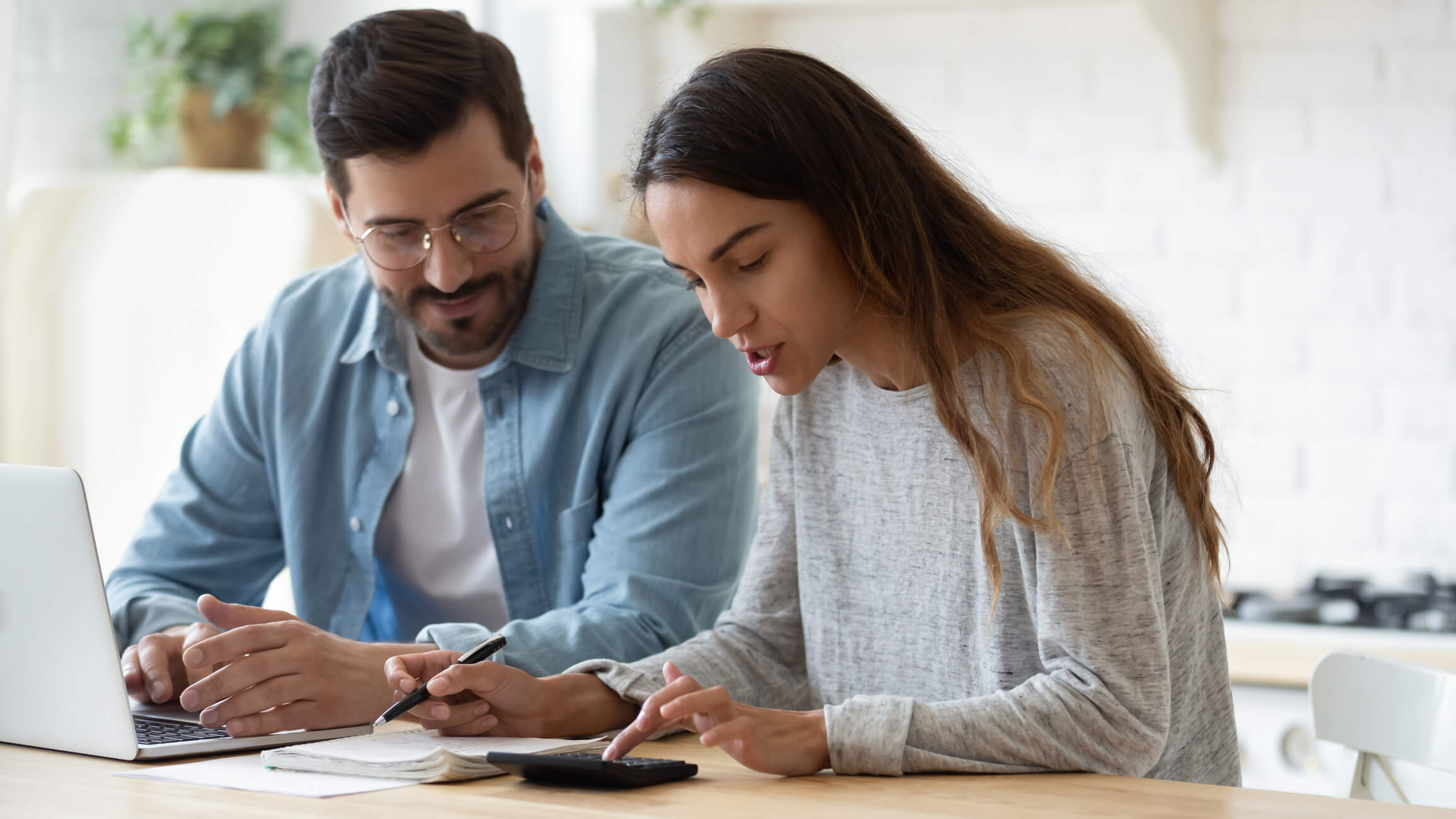 Un couple étudie le budget de sa construction, ordinateur et calculatrice sur la table
