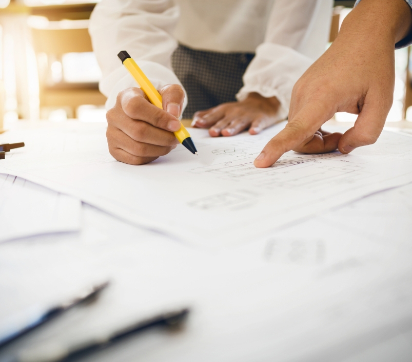 Deux personnes annotent un plan de construction, crayon en main
